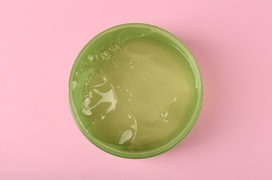 Jar of aloe gel on pink background, top view