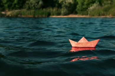 Photo of Red paper boat floating on river, space for text