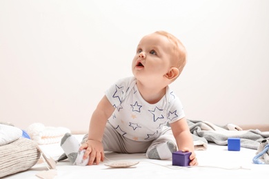 Little boy in cute clothes sitting on floor against light background. Baby accessories