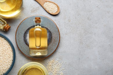 Sesame oil and seeds on light grey table, flat lay. Space for text