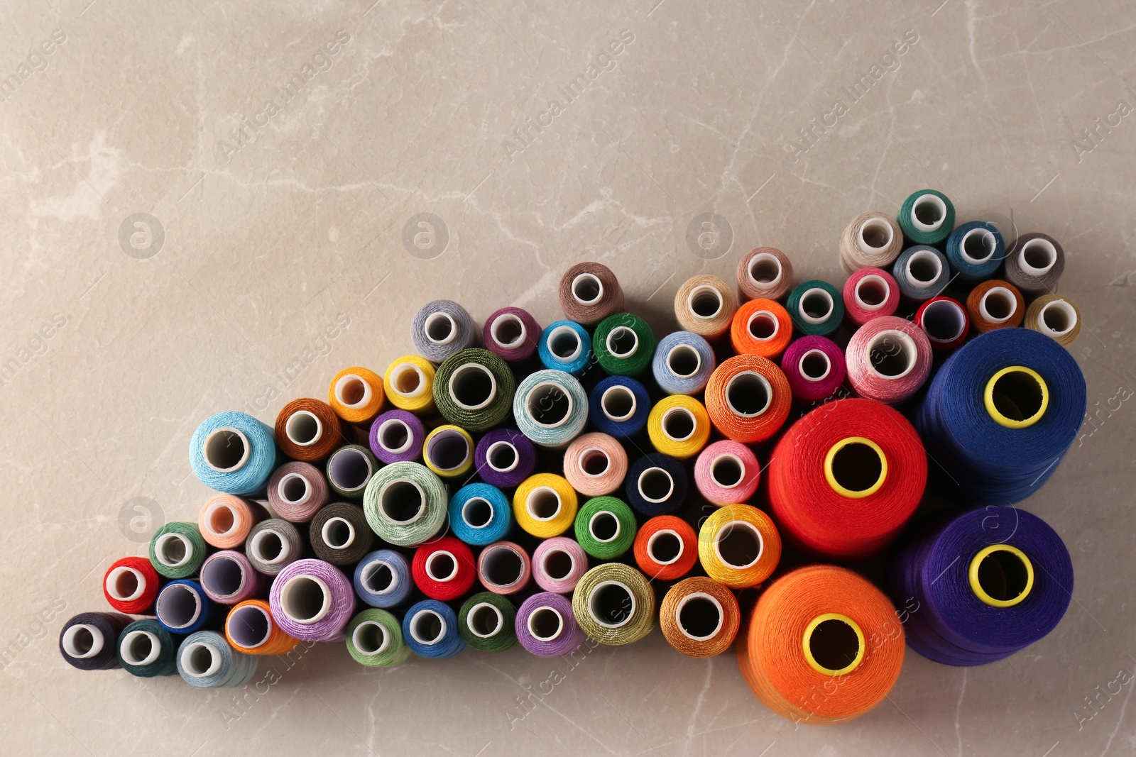 Photo of Set of color sewing threads on light grey table, flat lay