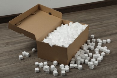 Photo of Cardboard box and styrofoam cubes on wooden floor indoors