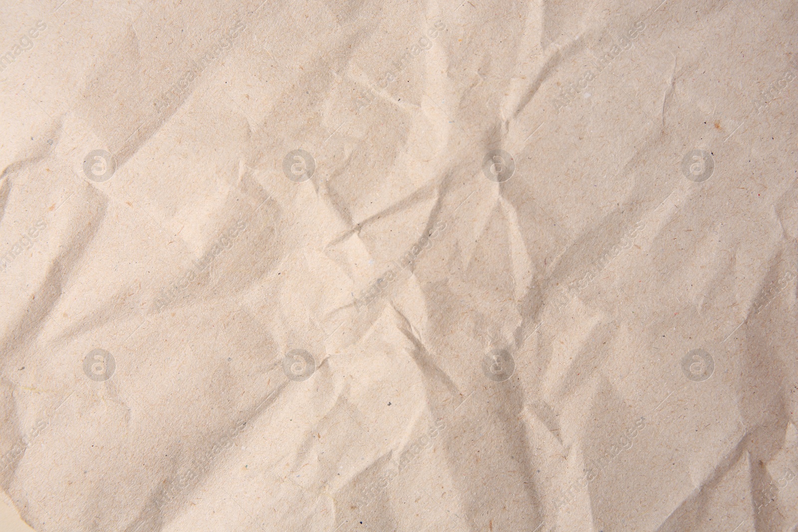 Photo of Sheet of crumpled light brown paper as background, top view