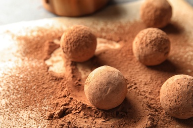 Photo of Sweet chocolate truffles powdered with cacao on parchment paper, space for text