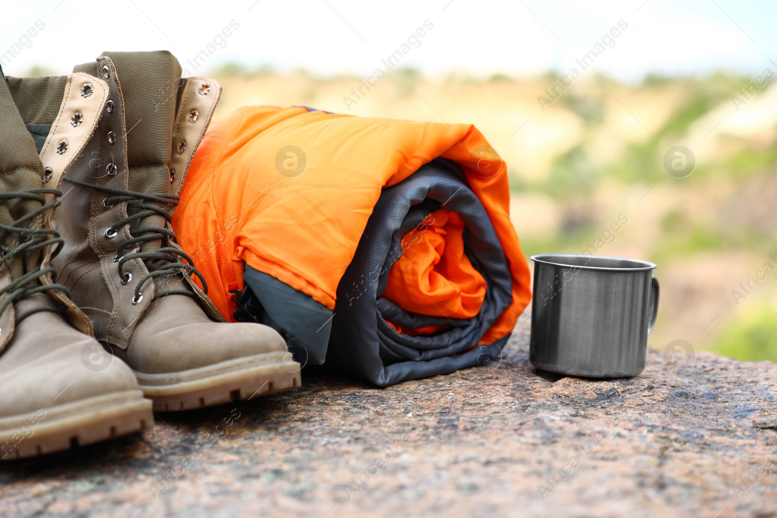 Photo of Sleeping bag, cup and boots outdoors on sunny day