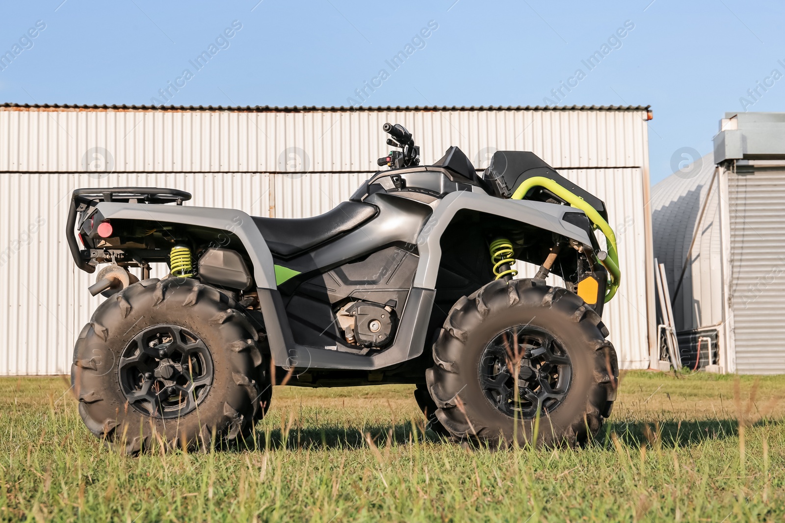 Photo of Modern quad bike in field near hangars on sunny day