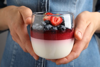 Photo of Woman holding glass dish delicious panna cotta with berries, closeup