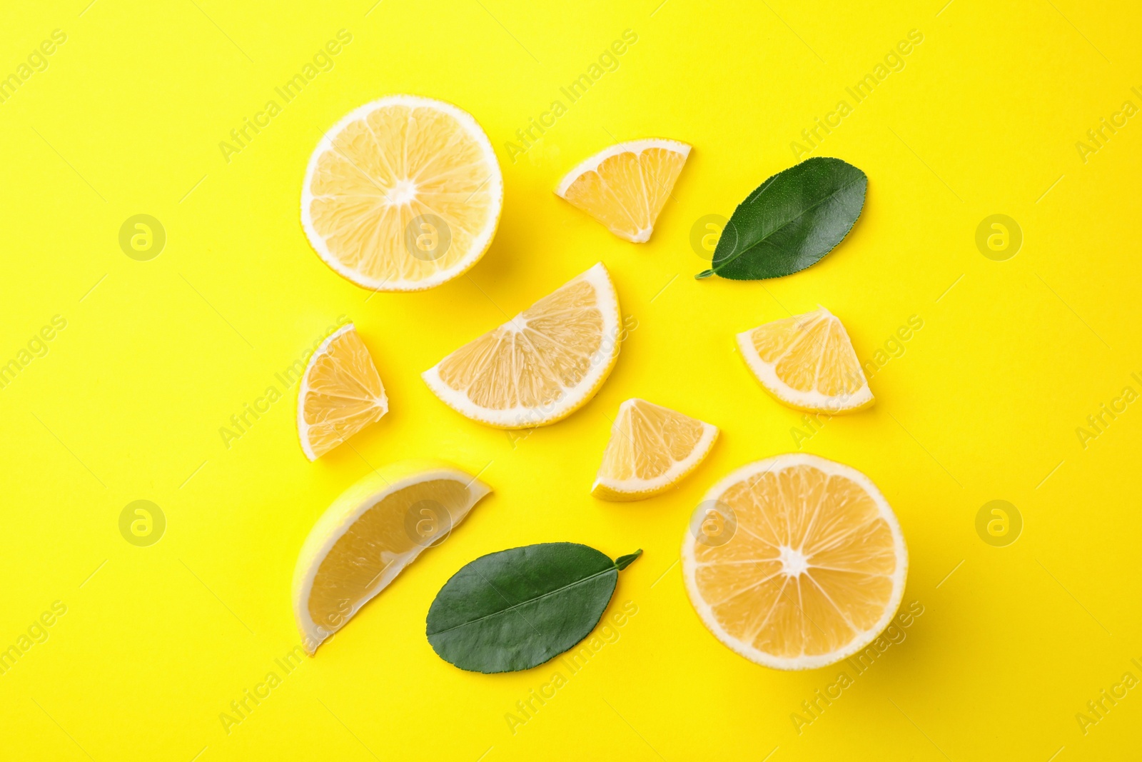 Photo of Fresh lemons and leaves on yellow background, flat lay