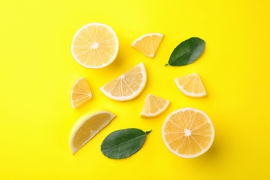Photo of Fresh lemons and leaves on yellow background, flat lay