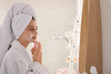 Photo of Beautiful teenage girl applying cleansing foam onto face in bathroom. Skin care cosmetic