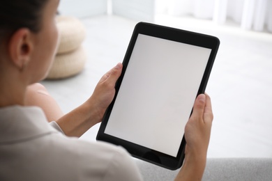 Woman using modern tablet at home, closeup. Space for design