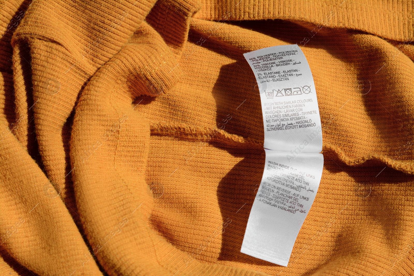 Photo of Clothing label on orange garment, top view