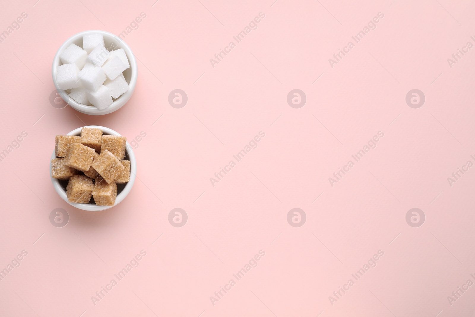 Photo of White and brown sugar cubes on pink background, flat lay. Space for text