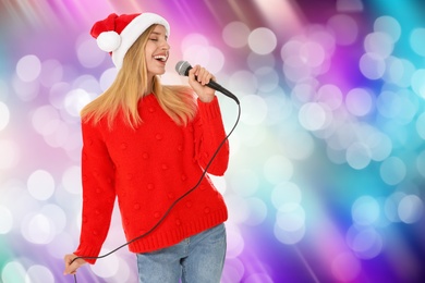 Happy woman in Santa hat singing on bright background, bokeh effect