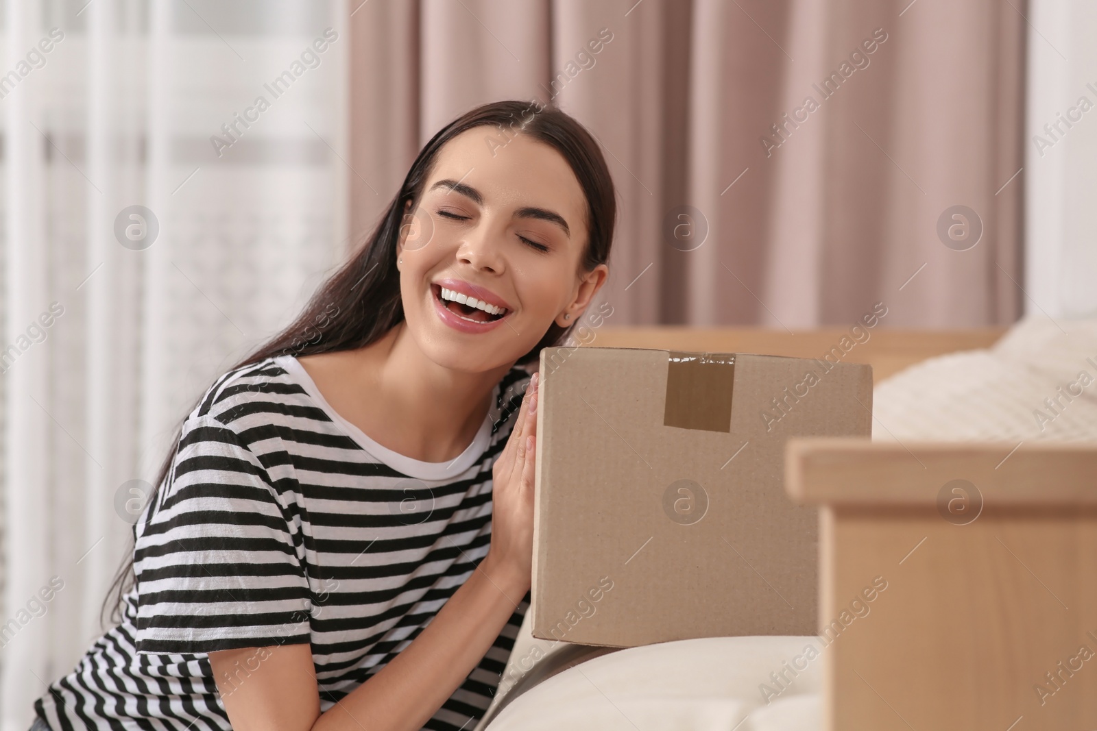 Photo of Happy young woman with parcel at home. Internet shopping