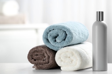 Photo of Clean towels and shampoo bottle on table. Space for text