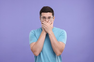 Photo of Embarrassed man covering mouth on purple background