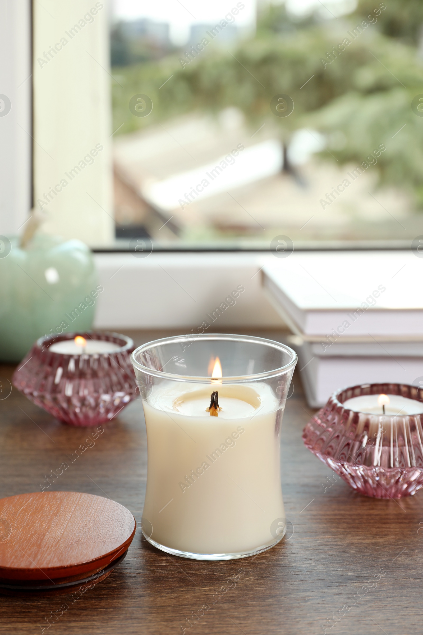 Photo of Burning candles with books on wooden window sill