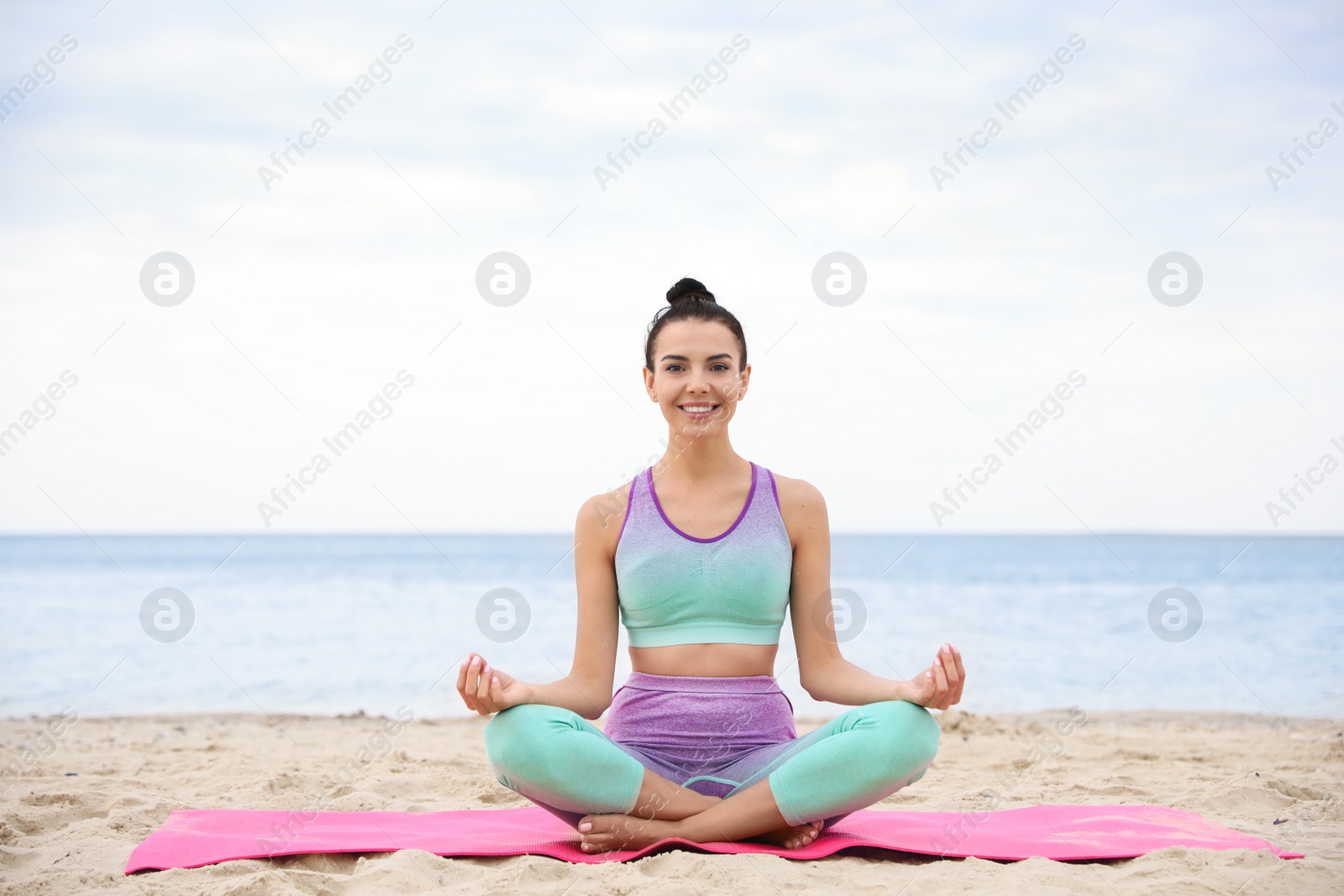 Photo of Young woman practicing yoga on beach. Body training