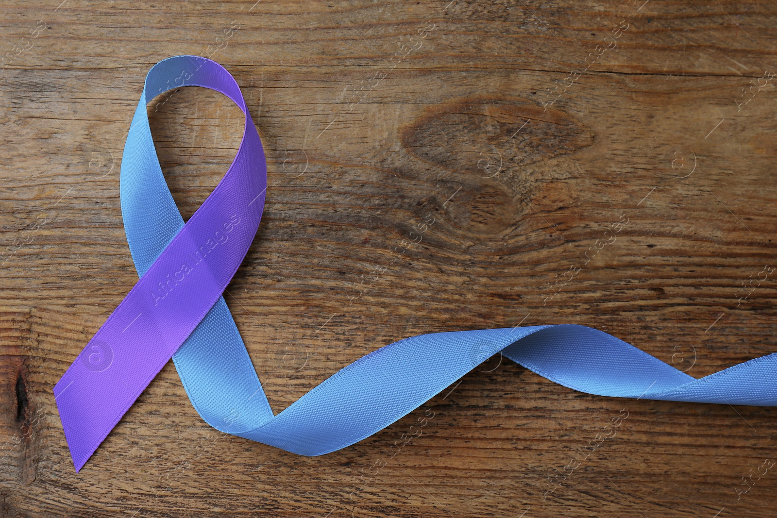 Image of World Arthritis Day. Blue and purple awareness ribbon on wooden background, top view