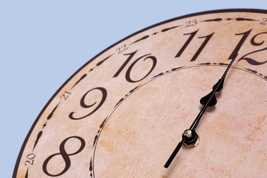 Stylish round clock on light blue background, closeup. Interior element