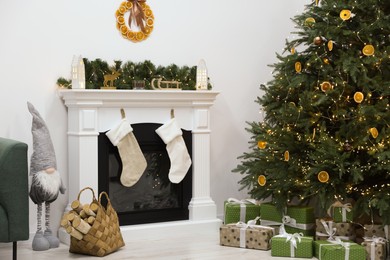 Photo of Cozy living room with fireplace and gifts under Christmas tree. Interior design