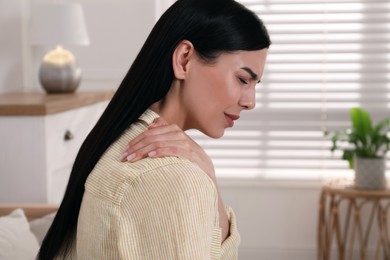 Photo of Woman suffering from shoulder pain at home