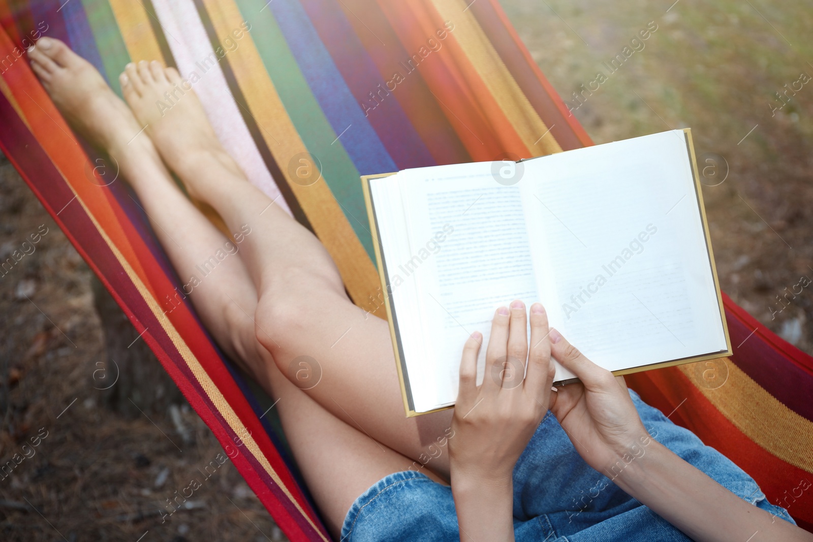 Photo of Woman with book relaxing in hammock outdoors on summer day, closeup