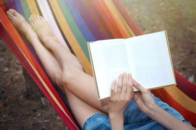 Photo of Woman with book relaxing in hammock outdoors on summer day, closeup