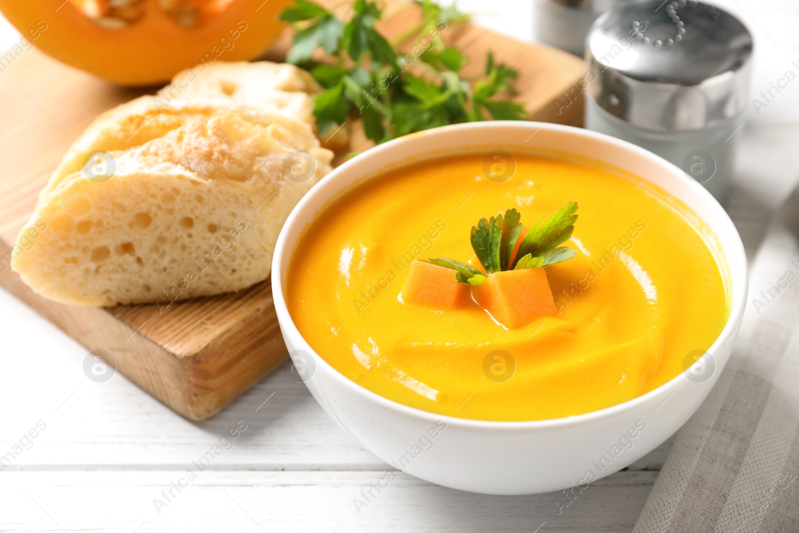 Photo of Bowl with delicious pumpkin cream soup and bread on wooden table