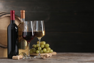 Photo of Composition with glasses and bottles of different wine on wooden table. Space for text