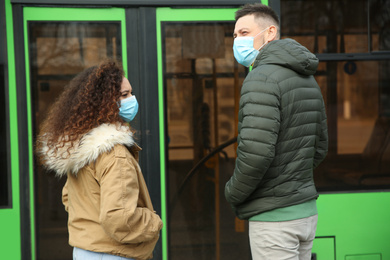 People with disposable masks near bus outdoors. Virus protection
