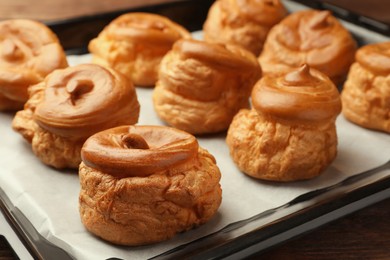 Photo of Delicious fresh profiteroles on baking pan, closeup