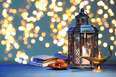 Arabic lantern, Quran, dates and Aladdin magic lamp on table against light blue background with blurred lights. Space for text