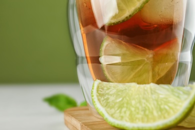 Photo of Glass of tasty ice tea with lime on table, closeup