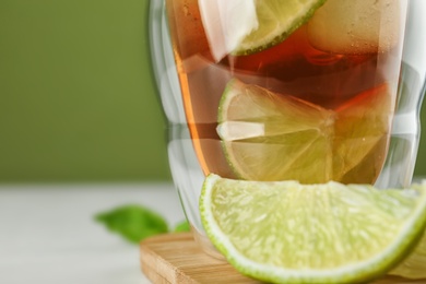 Glass of tasty ice tea with lime on table, closeup