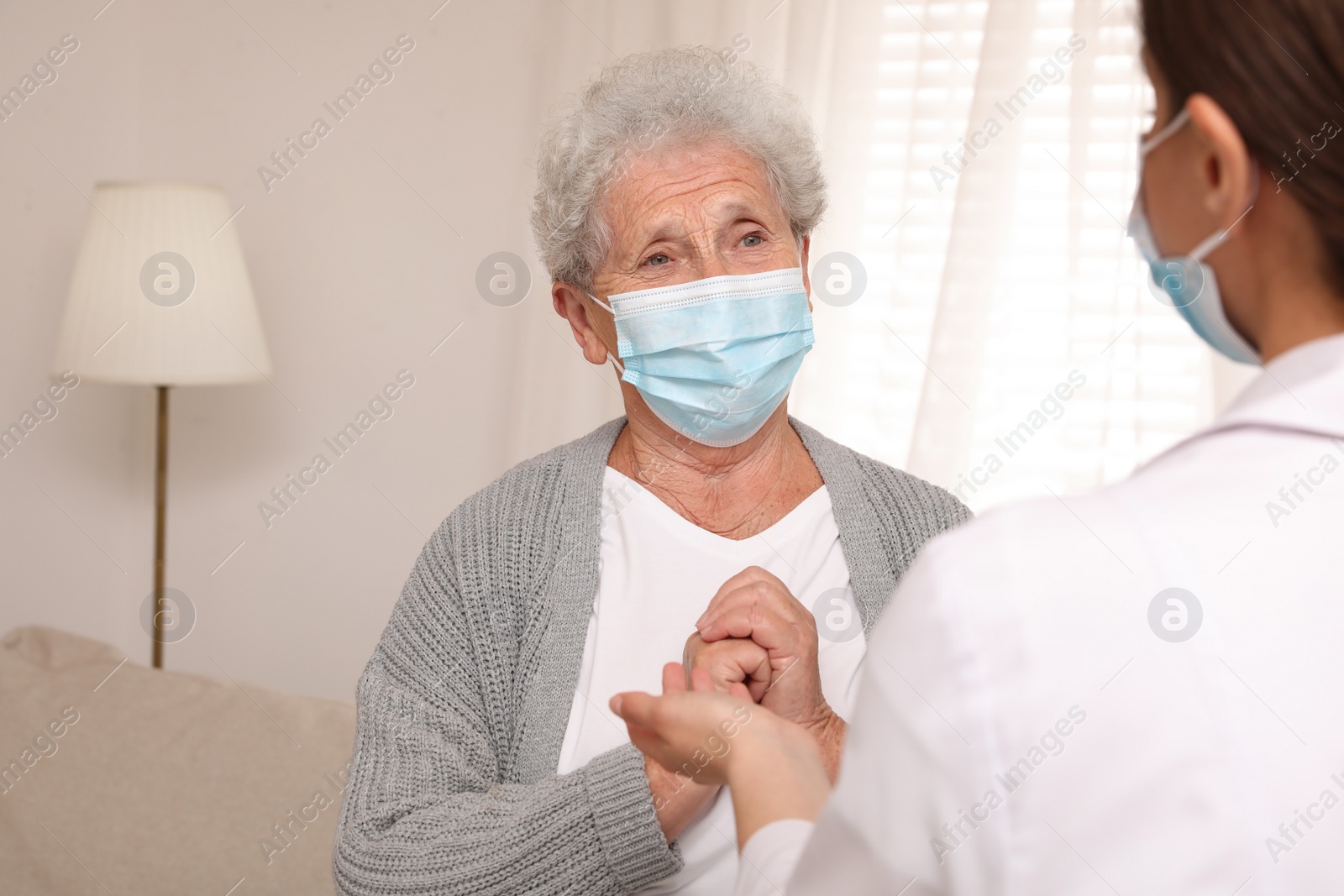 Photo of Doctor taking care of senior woman with protective mask at nursing home