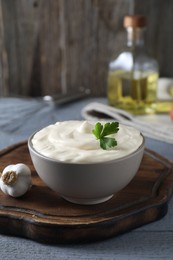 Photo of Tasty mayonnaise in bowl and garlic on light grey wooden table