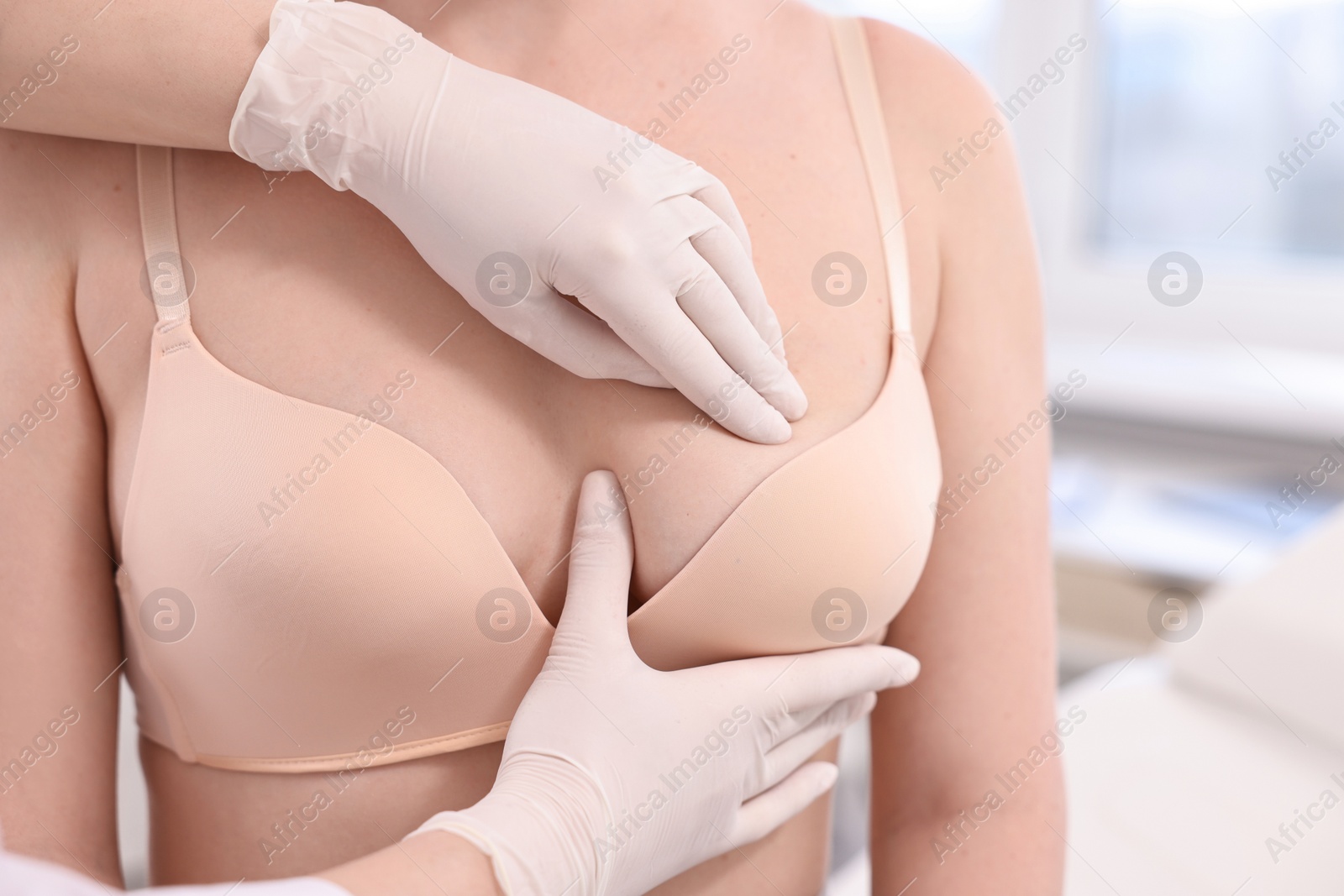 Photo of Mammologist checking woman's breast in hospital, closeup