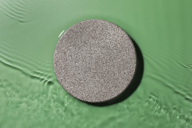 Photo of Presentation for product. Stone podium in water on green background, top view