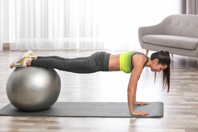 Young woman doing exercise with fitness ball at home