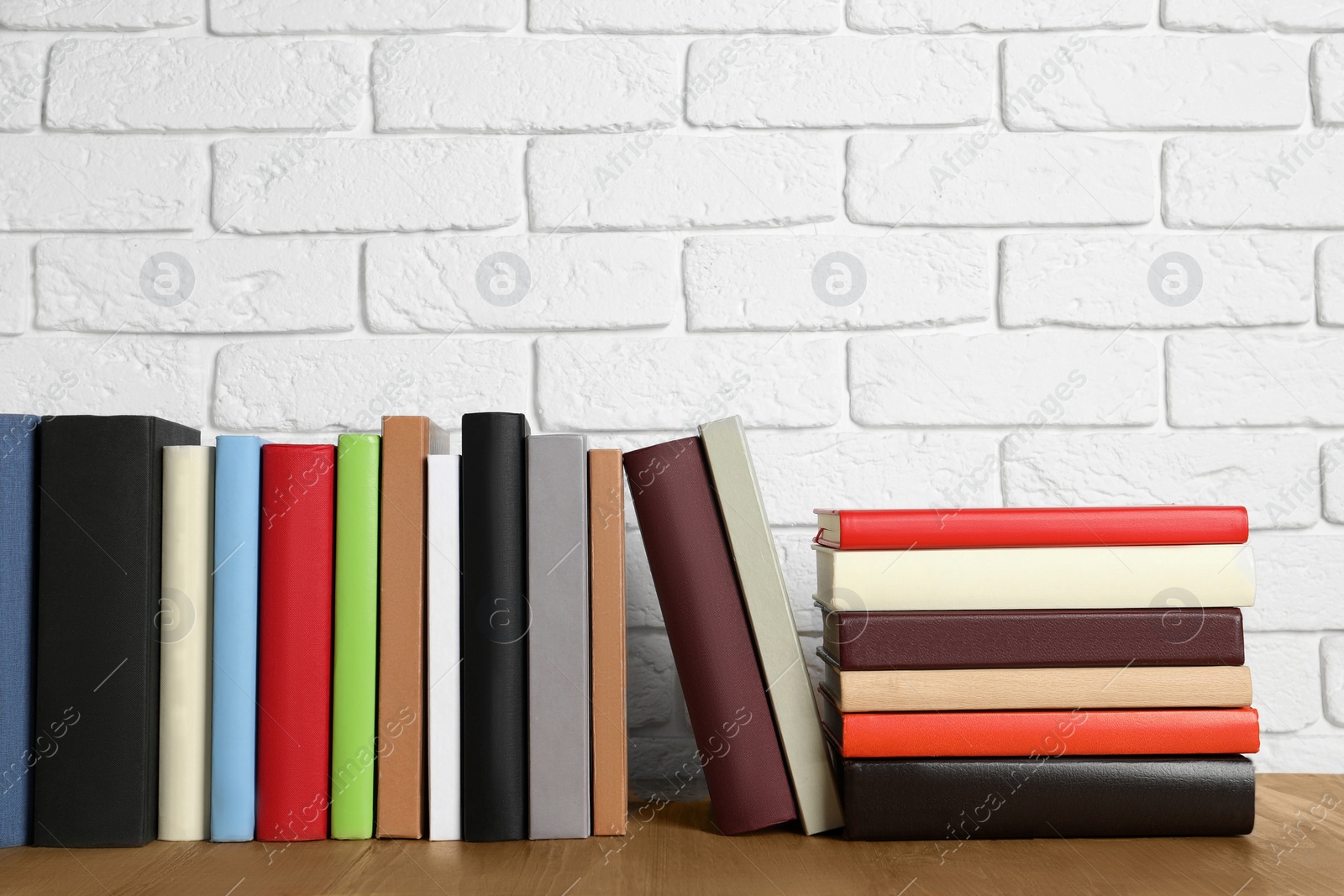 Photo of Books on wooden table near white brick wall