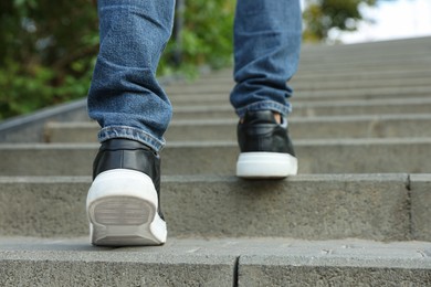 Photo of Man in stylish black sneakers walking up stairs, closeup