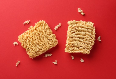 Photo of Blocks of quick cooking noodles on color background, flat lay