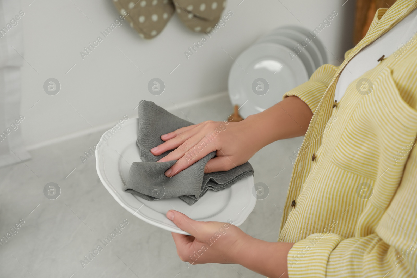 Photo of Woman wiping plate with towel at white marble table in kitchen, closeup