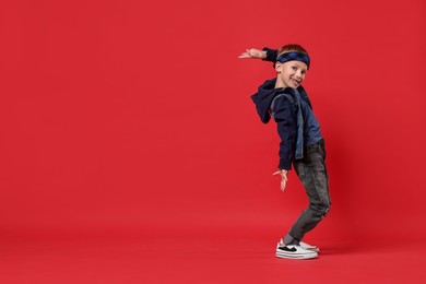 Photo of Happy little boy dancing on red background. Space for text