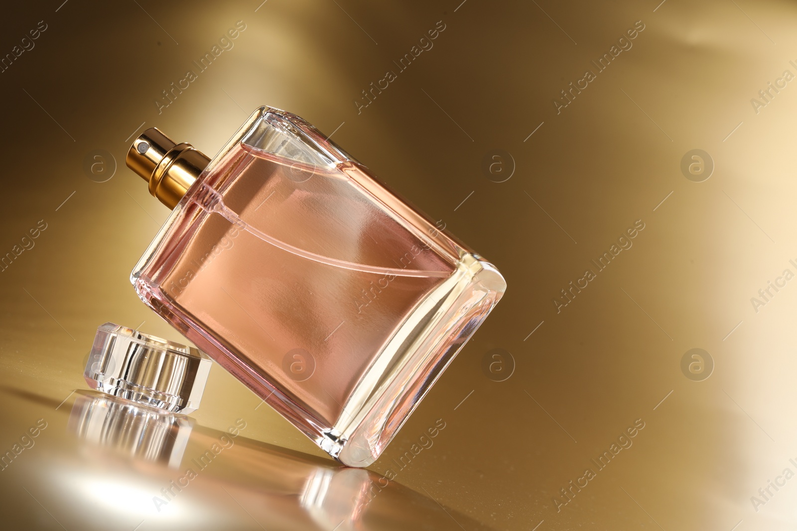 Photo of Luxury women's perfume. Sunlit glass bottle on golden background, space for text