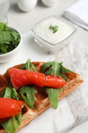 Fresh Belgian waffle with salmon and arugula on white table, closeup