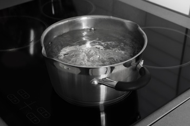 Photo of Pot with boiling water on electric stove in kitchen