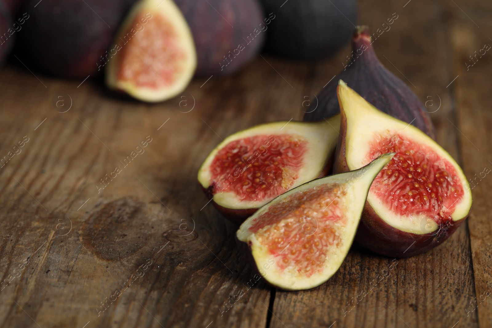 Photo of Whole and cut tasty fresh figs on wooden table, closeup. Space for text